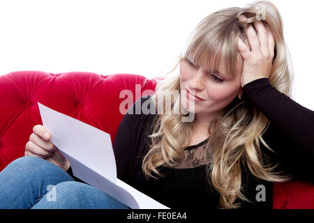 Jeune fille aux cheveux blonds sur canapé rouge got bad news in front of white background Banque D'Images