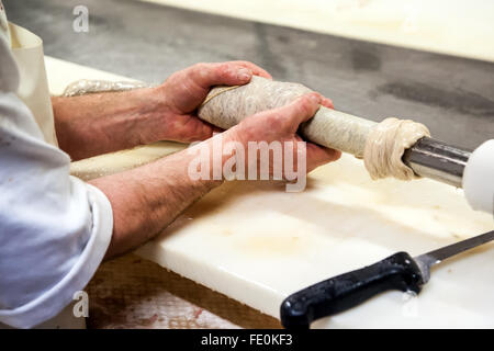 Close up of butcher mains préparation de caissons à remplir de farce dans une usine de transformation de salami Banque D'Images