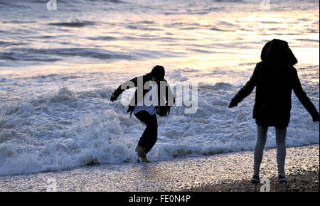 Brighton, UK. 3 Février, 2016. Météo France : un jeune homme jouit en esquivant les vagues au coucher du soleil sur Brighton après une journée froide mais ensoleillée sur la côte sud Crédit : Simon Dack/Alamy Live News Banque D'Images