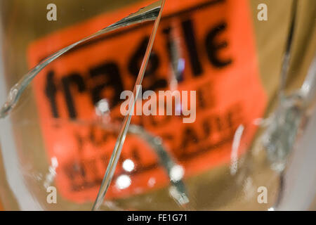 Grande fissure dans le verre en face d'une orange 'fragile a manipuler avec précaution' sign Banque D'Images