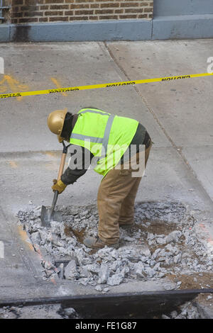 Travailleur de la construction de retirer manuellement les débris de béton cassé un trou dans le trottoir avec une pelle (FE1G84, FE1G8A, G1FE8C) Banque D'Images