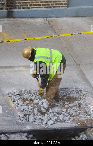 Travailleur de la construction de retirer manuellement les débris de béton cassé un trou dans le trottoir avec une pelle (FE1G84, FE1G87, FE1G8C) Banque D'Images