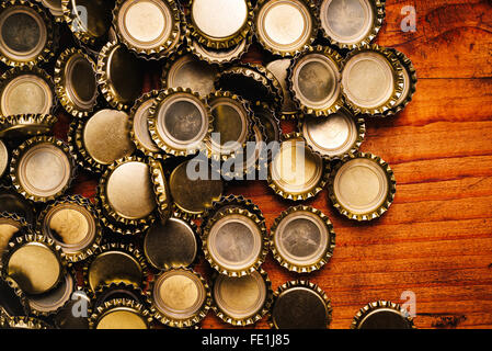 Gros tas de capsules de bouteilles de bière sur le bureau en bois de chêne rustique Banque D'Images