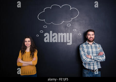 Heureux couple debout avec les bras croisés et d'avoir les mêmes pensées au fond du noir Banque D'Images