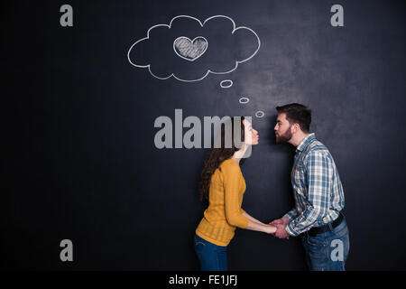 Heureux loving young couple holding hands et les baisers sur fond plaqué Banque D'Images