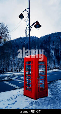 La boîte de téléphone rouge classique sur la rue enneigée à Sinaia, Carpates, Roumanie Banque D'Images