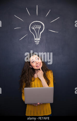 Une jeune femme ordinateur portable et à la recherche jusqu'au fond du tableau Banque D'Images
