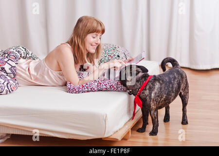 Femme de vous détendre dans le lit avec un joli chien. Banque D'Images