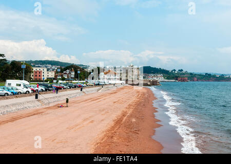 Les vacanciers à pied le long de la promenade ou de la plage, sur les crêtes des Whitecaps de petites vagues laisser la mousse sur le sable rouge Banque D'Images