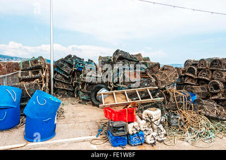 Des casiers à homard et des engins de pêche soigneusement empilés sur le côté port prêt à charger dans un bateau de pêche commerciale, le port de Paignton Banque D'Images