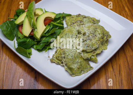 Ravioles d'épinards avec sauce pesto dans une assiette avec une salade de tomates et d'avocat Banque D'Images