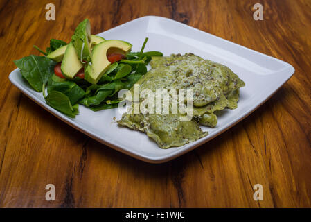 Ravioles d'épinards avec sauce pesto dans une assiette avec une salade de tomates et d'avocat Banque D'Images