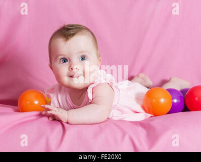 Adorable happy baby girl sur fond rose Banque D'Images