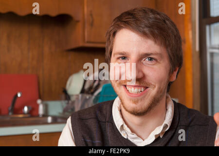 Jeune homme aveugle assis dans sa cuisine et smiling Banque D'Images