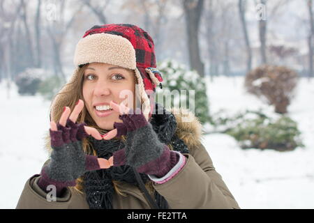 Girl making heart shape avec ses doigts en plein air d'hiver Banque D'Images