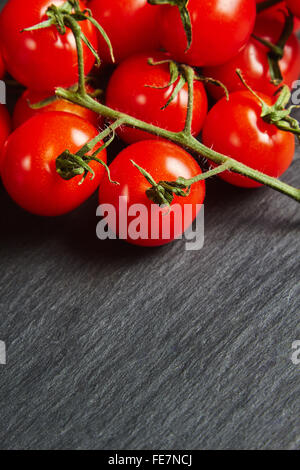 Tomates cerises sur une ardoise noire Banque D'Images