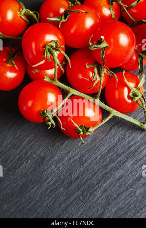 Tomates cerises sur une ardoise noire Banque D'Images