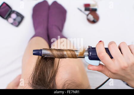 Vue de dessus d'un redressage fille ses cheveux alors qu'il était assis dans le lit Banque D'Images