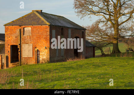 Une vieille ferme abandonnée avec barricadèrent les fenêtres et la maçonnerie baignée de soleil d'hiver, le Northamptonshire, Angleterre Banque D'Images