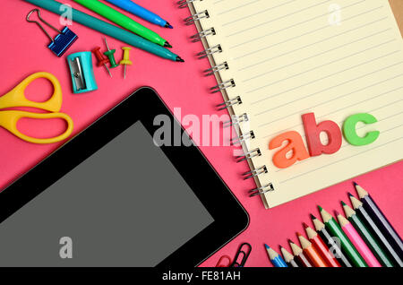 Tablette avec accessoires scolaires sur fond rose Banque D'Images