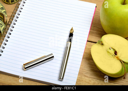 Ordinateur portable ouvert avec pomme fruit et centimétrique sur table Banque D'Images