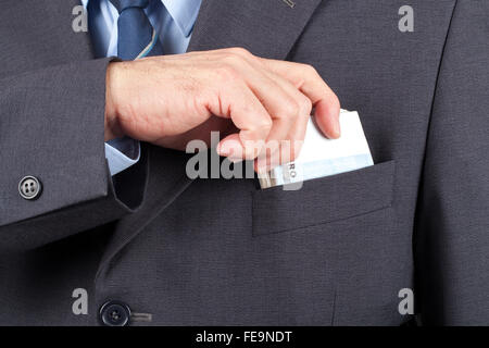 Man in suit mettre une liasse d'argent dans sa poche. Banque D'Images