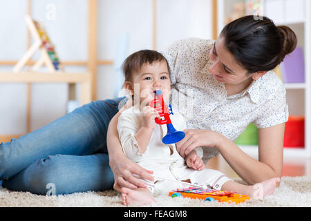 Bébé et sa mère jouer jouets musicaux Banque D'Images