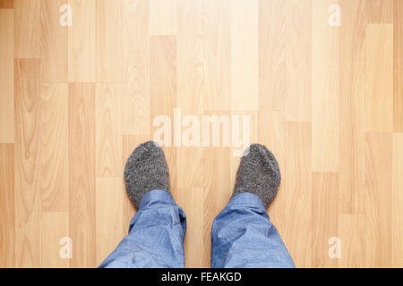 Les pieds mâles pantalon bleu et gris en bas de laine se tenir sur un plancher en bois Banque D'Images