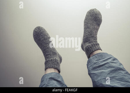 Les pieds mâles dans des chaussettes en laine gris style rétro, correction tonale filtre photo Banque D'Images