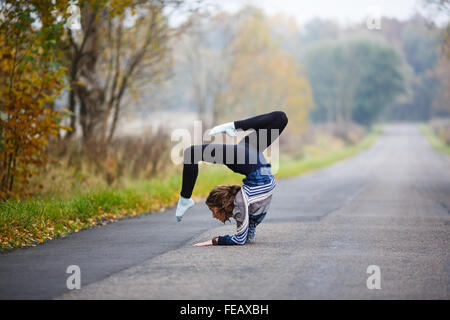 Jeune gymnaste professionnel rend se divise sur la route au moment de l'automne Banque D'Images