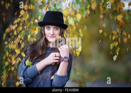 Portrait de belle fille dans un chapeau sur un fond de feuilles jaunes Banque D'Images