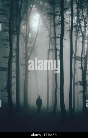 Silhouette of man à travers les arbres dans la forêt de brouillard mystérieux sur Halloween Banque D'Images