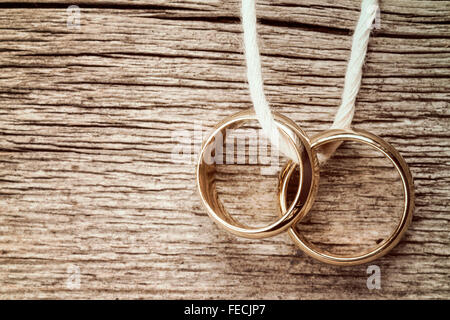 Les anneaux de mariage pendaison sur corde sur fond de bois. Image vintage. Banque D'Images