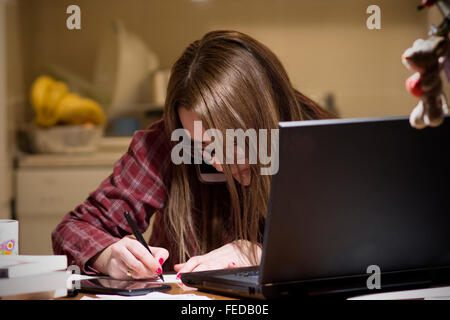 Jeune femme de payer les factures en ligne tard dans la soirée après avoir terminé tous les travaux de sa maison, assis au bureau avec ordinateur, b Banque D'Images