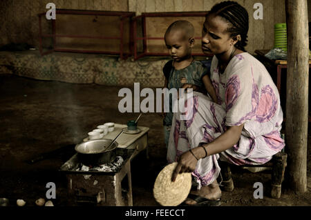 Femme éthiopienne avec son enfant la préparation du café fraîchement moulu à l'intérieur de sa maison dans Berhale, région Afar, Ethiopie Banque D'Images