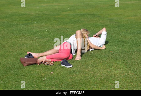 Les amateurs anonymes enlacés sur l'herbe dans un parc public. Juillet 2015 Banque D'Images