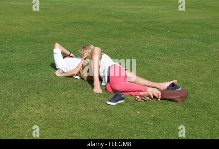 Les amateurs anonymes enlacés sur l'herbe dans un parc public. Juillet 2015 Banque D'Images