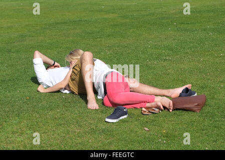 Les amateurs anonymes enlacés sur l'herbe dans un parc public. Juillet 2015 Banque D'Images