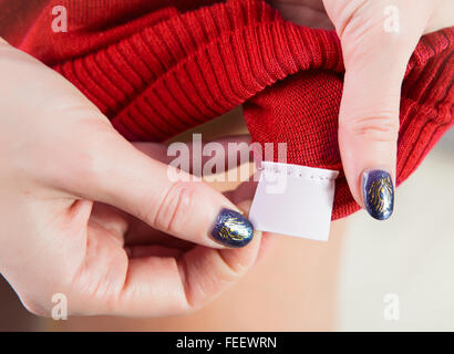 Libre de woman's hands holding empty vêtements étiquette pour tout texte d'informations Banque D'Images