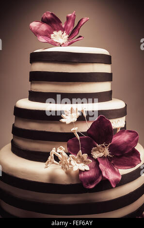 Détails d'un mariage ou d'un gâteau d'anniversaire, triple taille, en studio sur fond blanc. Purple fleurs de sucre comme décoration principale. Banque D'Images