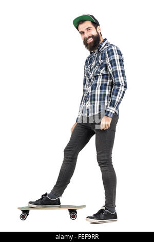 Hipster positif rire avec smiley permanent piercing sur planche Vue de côté. La pleine longueur du corps portrait isolated over white Banque D'Images