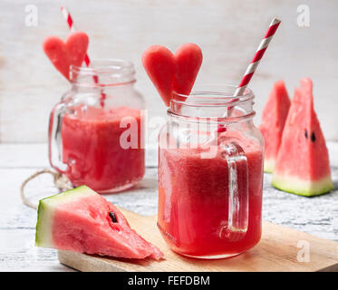 Smoothie pastèque fraîche dans un pot Mason, tranches de melon d'eau sous la forme de cœur sur le fond en bois Banque D'Images