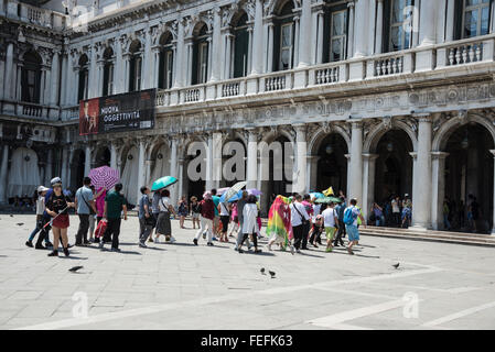 Un groupe de touristes asiatiques d'ombre du soleil avec leur parapluie qu'ils sont conduits sur une visite guidée sur la Piazza San Marco ( Banque D'Images