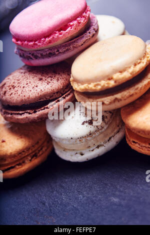 Pile de macarons sur une ardoise noire, en différentes couleurs, vue en gros Banque D'Images