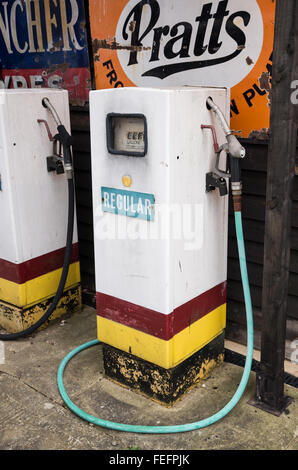 Pompe à gaz / essence vintage à Battlesbridge Motorcycle Museum dans l'Essex, UK, avec les panneaux publicitaires rétro en arrière-plan. Banque D'Images