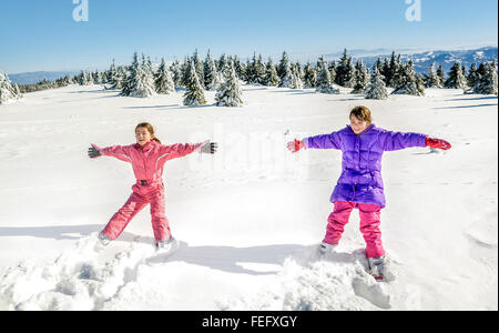 Deux petites filles de tomber et s'amuser sur la neige Banque D'Images