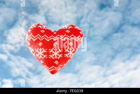 Coeur rouge textile avec flocons de neige avec des nuages en arrière-plan Banque D'Images