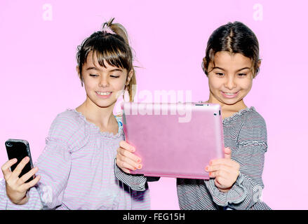 Cute little girls making avec selfies rose isolé sur tablette Banque D'Images