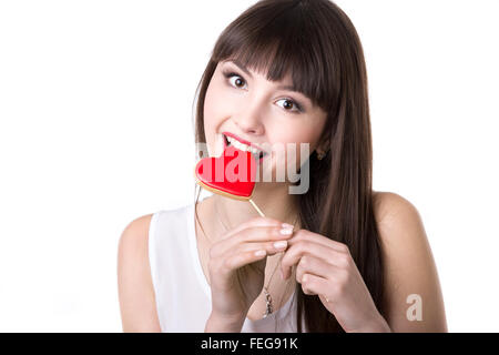 Portrait Portrait of young Beautiful woman holding ludique rouge en forme de coeur délicieux cookie, le bouffon, mordre biscuit Banque D'Images