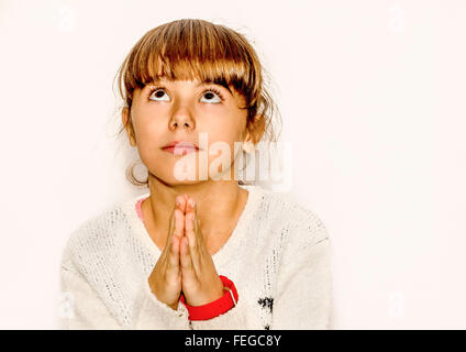 Belle petite fille priant et en regardant vers le haut, isolated on white Banque D'Images